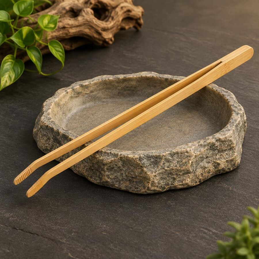 Bamboo reptile feeding tongs resting on a stone-effect feeding dish