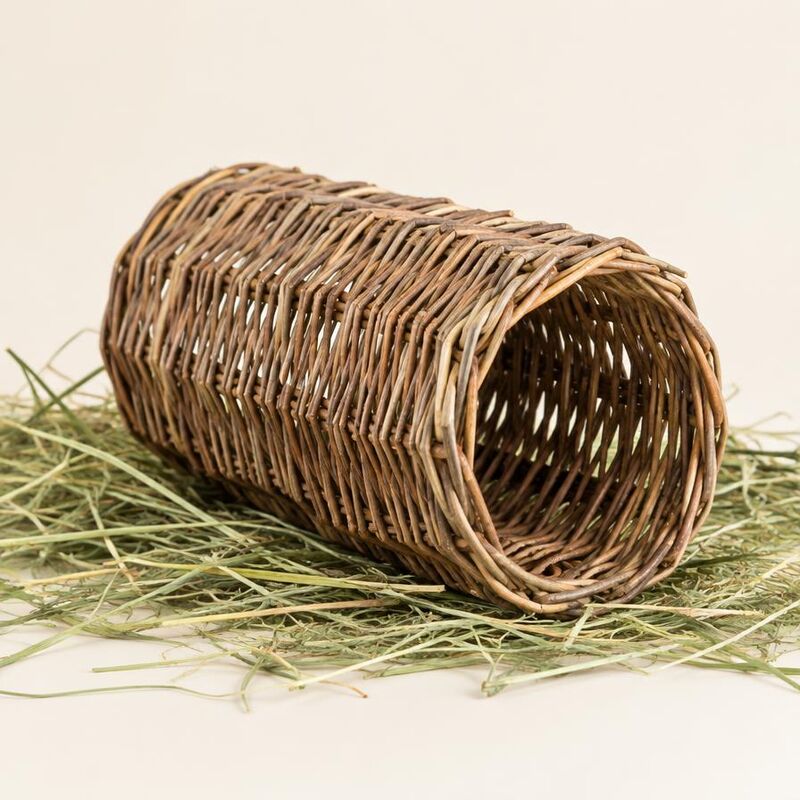 Woven willow chew tunnel resting on hay