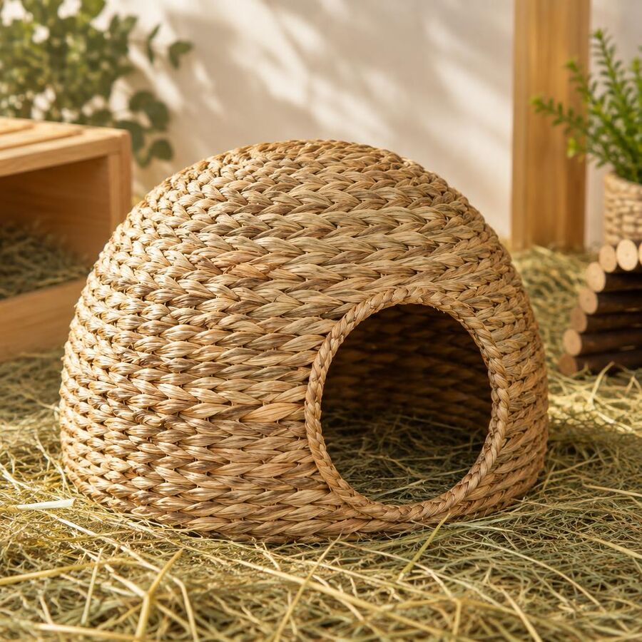 Dome-shaped woven seagrass hideaway on a bed of hay